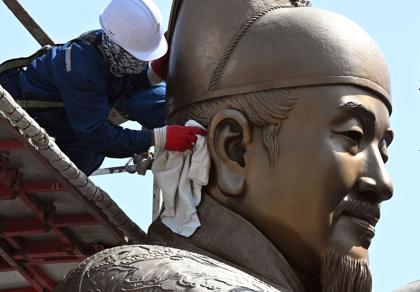 A worker wipes the bronze statue of King Sejong