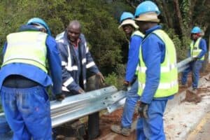 Contractors install new guardrails along the side of the road.