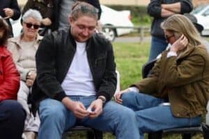 Stirling Andrew Levesley listens tearfully to kind words being said of his mother as he sits next to his sister.