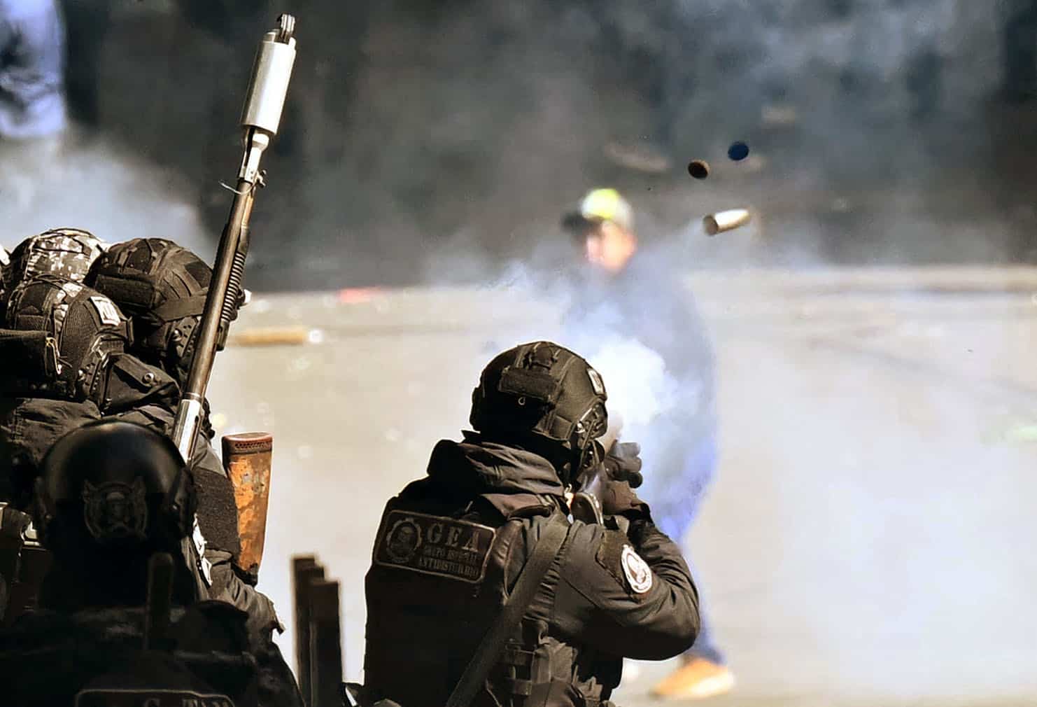 A Bolivian riot police officer shoots at demonstrators