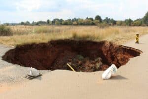 The sinkhole that caved in onto the tarred road surface has grown to such an extent that the Goudvlakte sign has fallen into it.