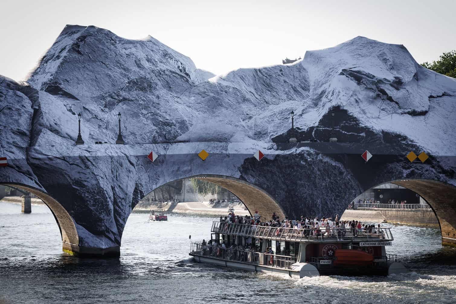 A tourist boat sails under the Pont-Neuf bridge