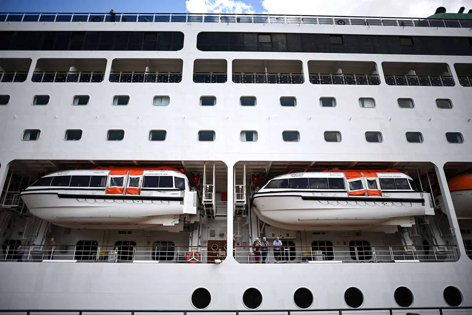 Passengers stand aboard the Bahamas-registered cruise ship Ambition