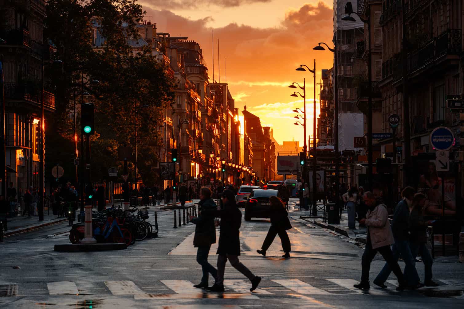 Pedestrians cross rue de Rivoli at sunset
