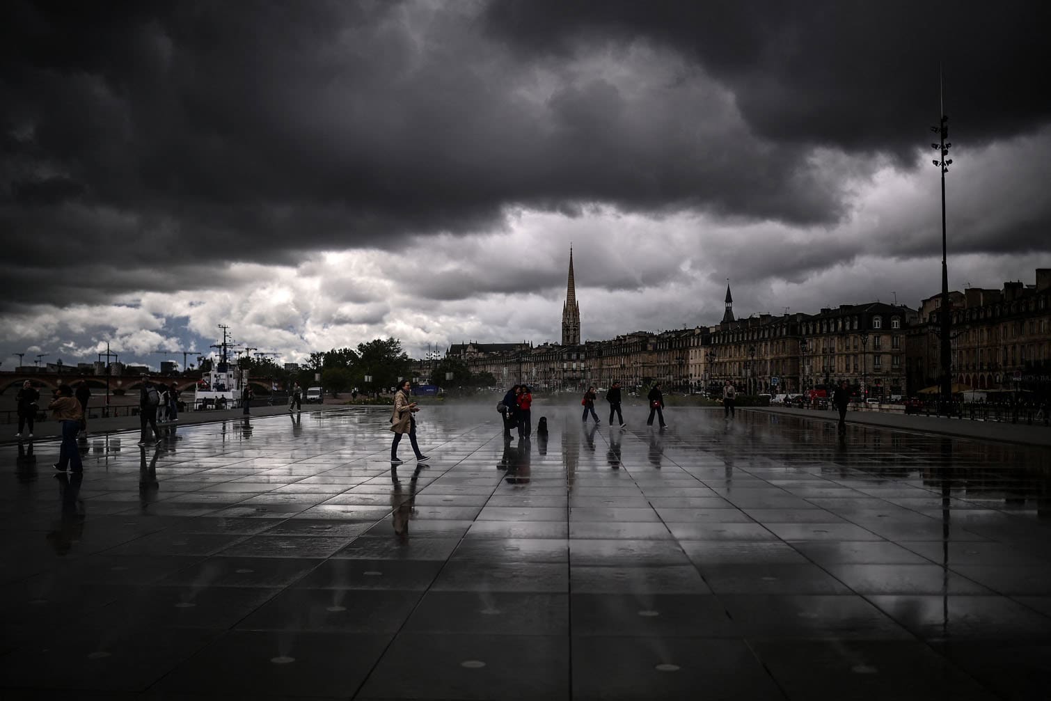 Passers-by walk across the Miroir d'Eau