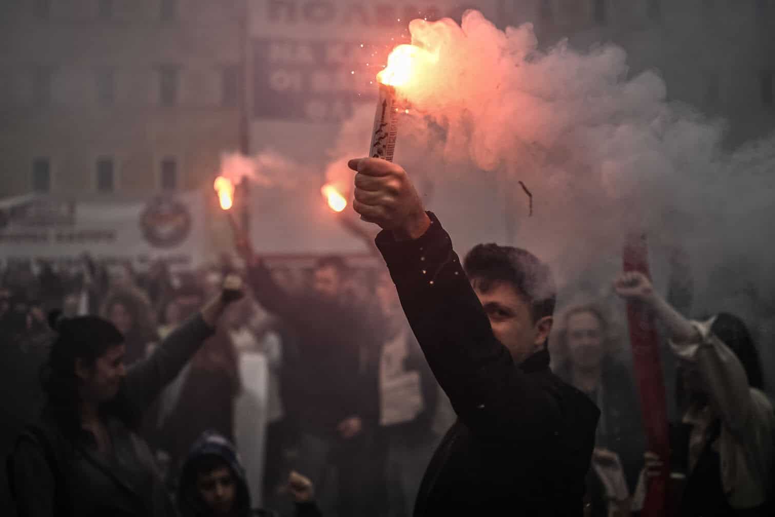 Demonstrators hold flares as they take part in a May Day