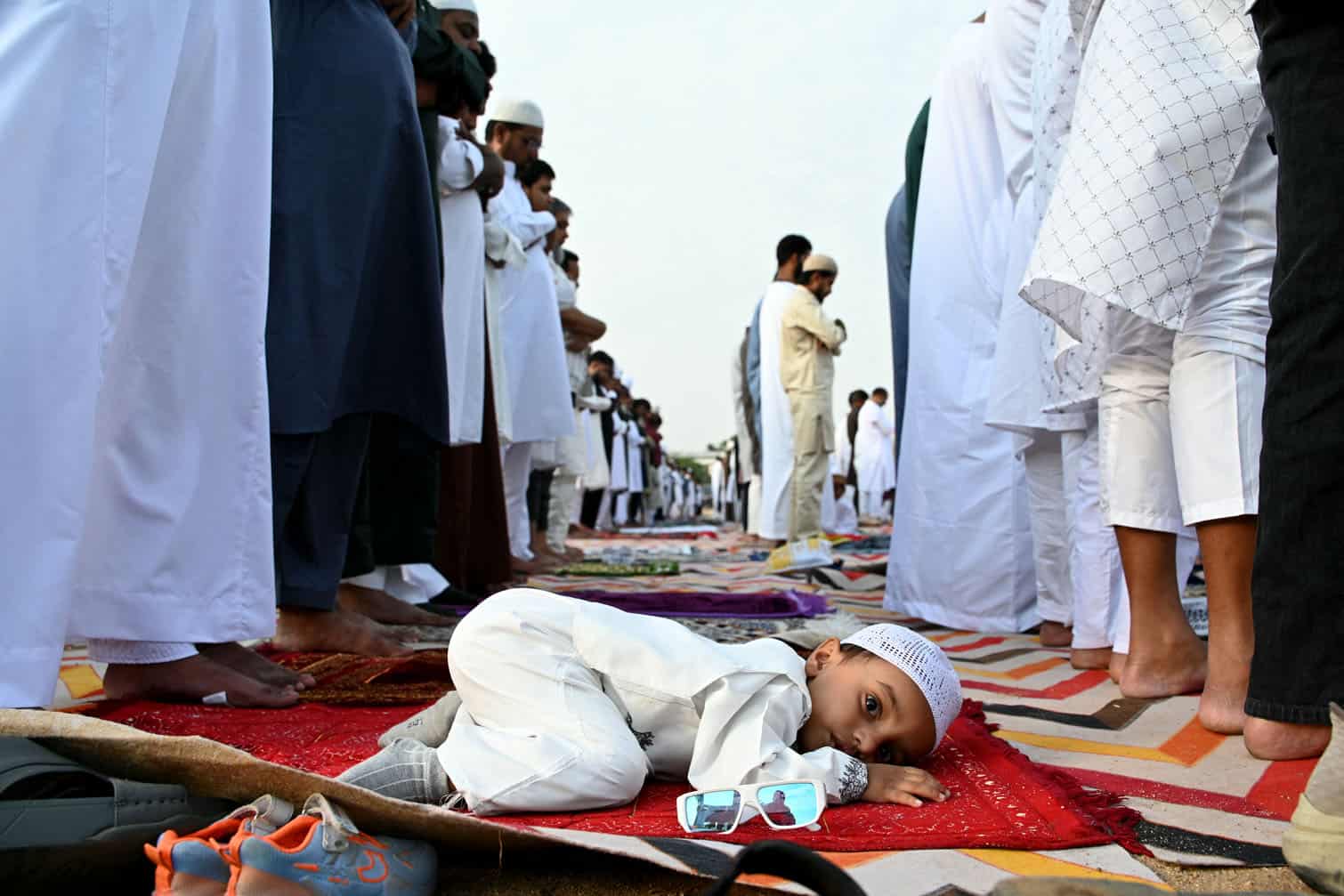 A child looks on as Muslim devotees offer Eid al-Adha prayers