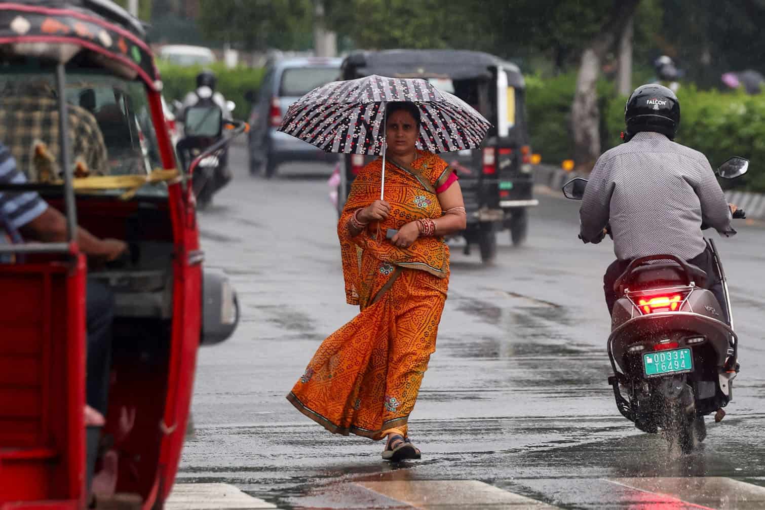 A woman carrying an umbrella walks during rainfall
