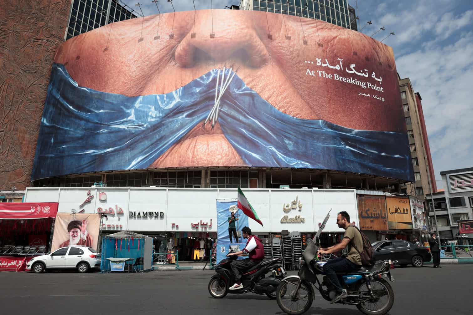 Motorists ride past an anti-US billboard