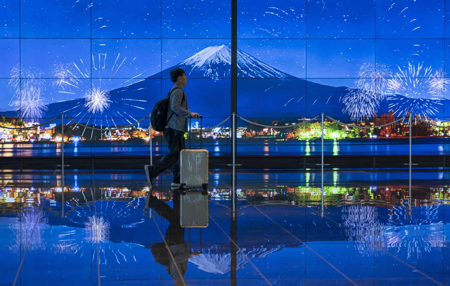A traveller walks past an image of Mount Fuji