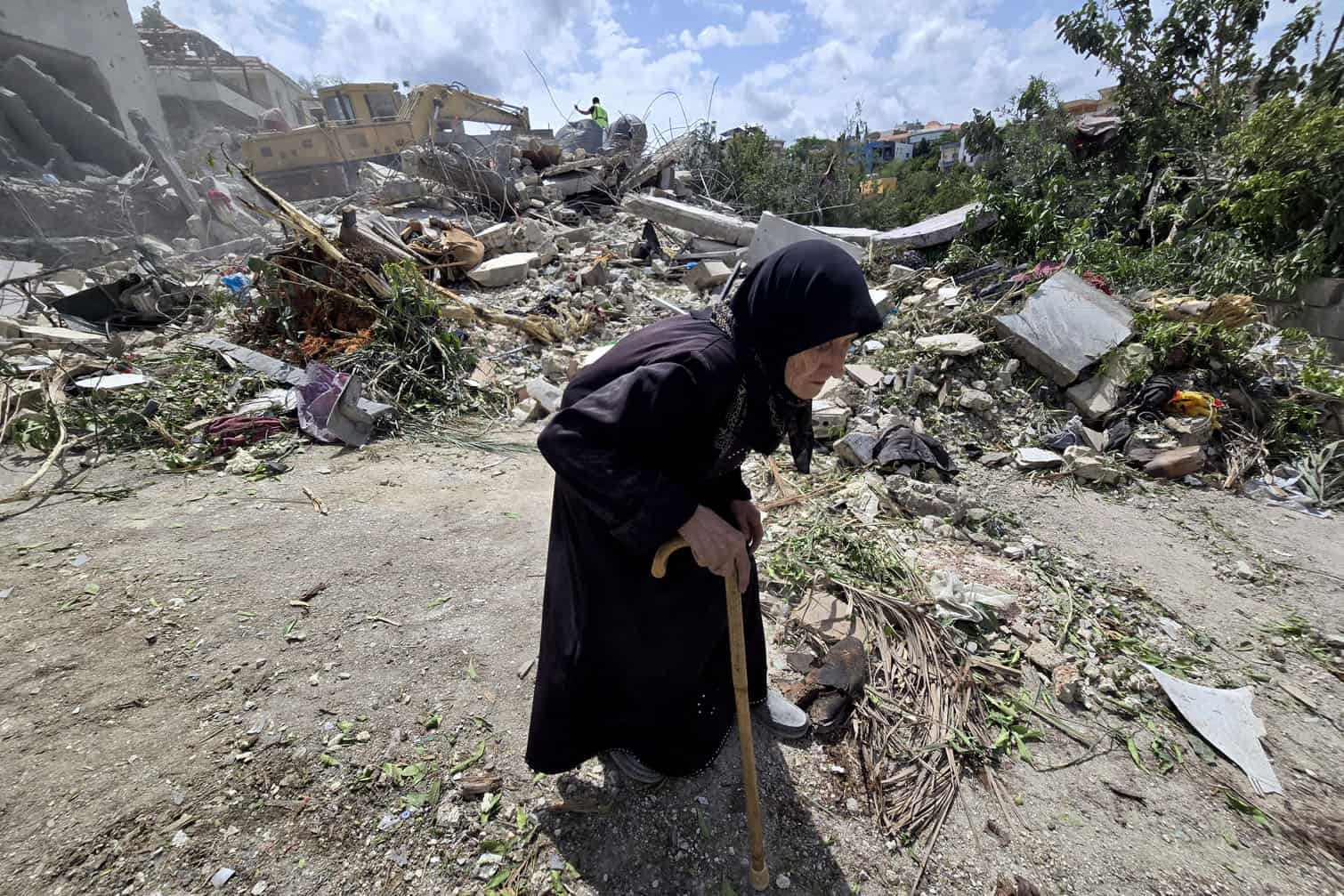 An elderly woman walks past Lebanese civil defence workers