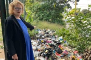 Ward 109 councillor Lori Coogan points to a large pile of illegally dumped waste between Robin Way and Marlboro Drive in Kelvin, raising concerns about environmental damage and public health risks in the area.