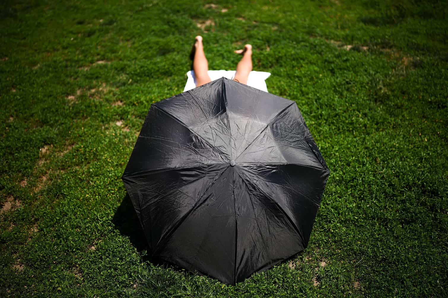 A person sits under an umbrella in Central Park