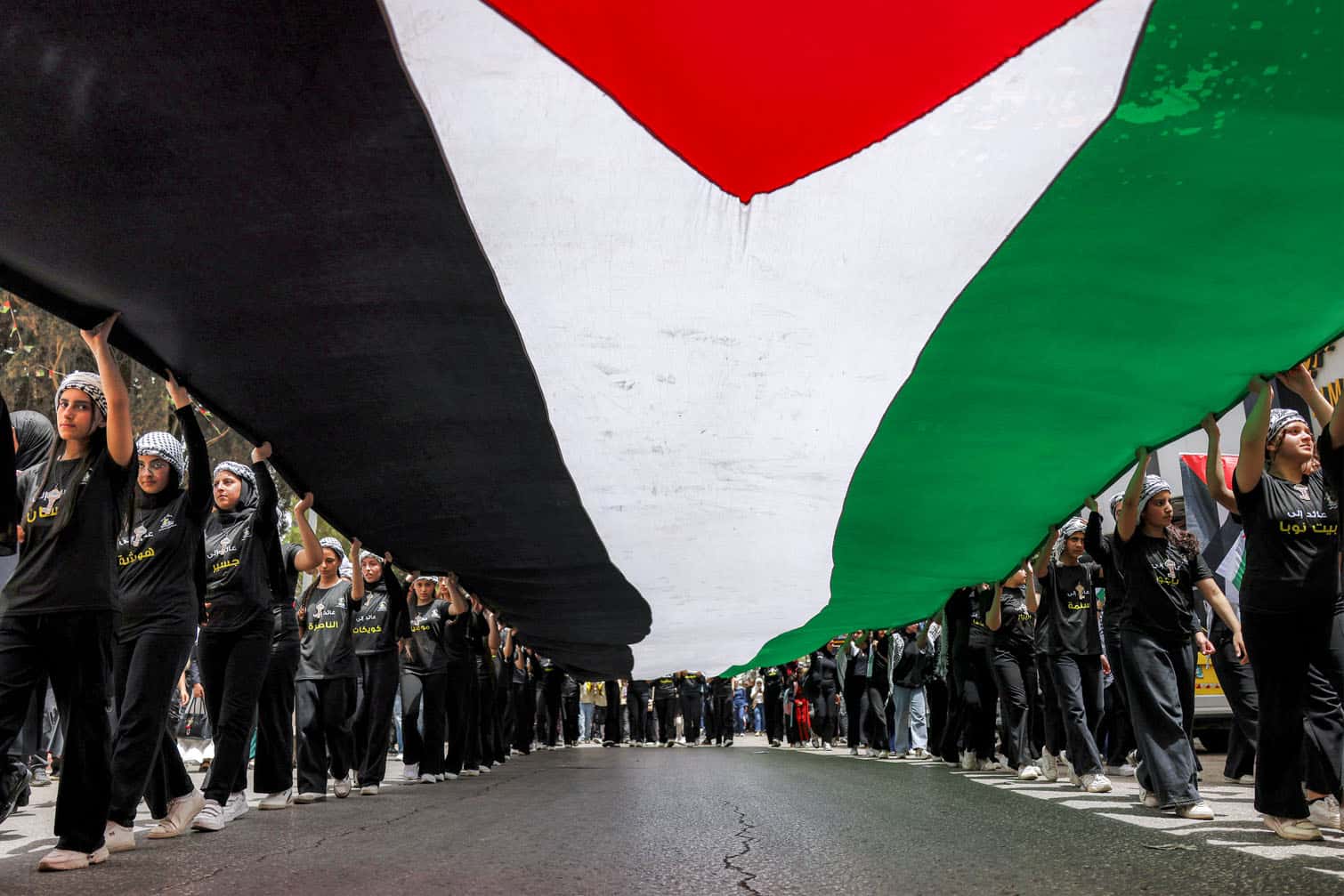 People march with a giant Palestinian flag