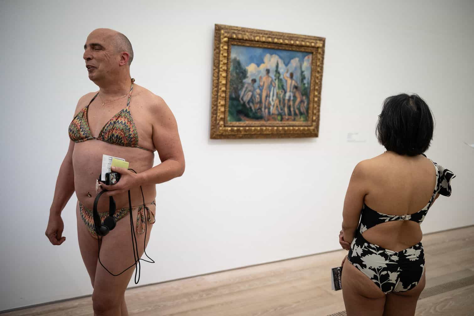 Visitors wearing swimsuits pass by the painting