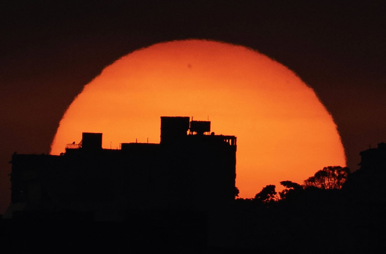 The sun sets behind buildings in Caracas