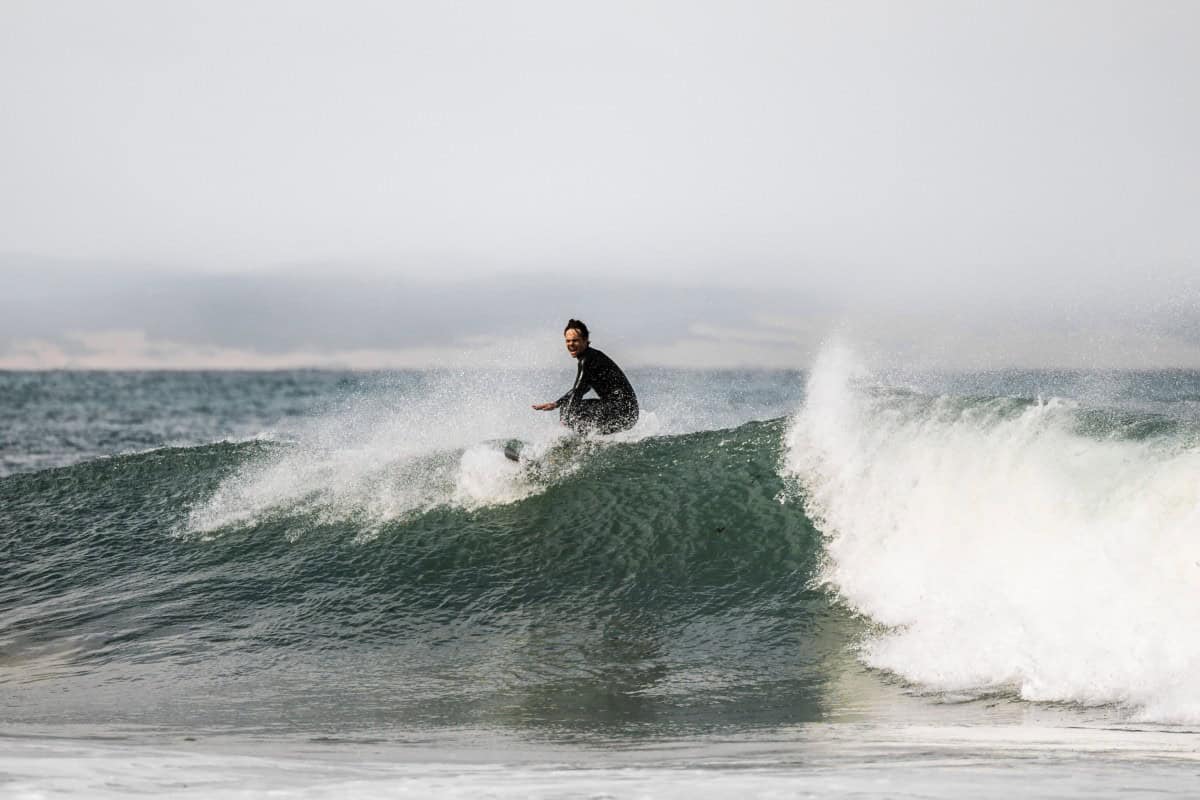 A surfer rides a wave in Jeffreys Bay, on March 7, 2026. Known worldwide simply as "J-Bay", South Africa's surf capital is grappling with uncertainty after losing its place on the World Surf League circuit in 2026. Dozens of surfers bobbed in the waves off Jefferys Bay and a stretch of signs touted surf schools, rentals and B&Bs, evidence of the small South African town's status as a global surf mecca. Its legendary point break secured J-Bay a place on a professional world surfing tour that has for decades drawn the sport's biggest names to this remote corner of the Eastern Cape almost every July. This year, though, the small town is missing out on the international spotlight after the World Surf League (WSL) abruptly pulled the South African stopover from its 2026 Championship Tour. It is a blow to the otherwise humble town of 30,000 inhabitants which made an occasion of an event that booked out its accommodation and brought in millions of dollars, by one estimate. (Photo by ILARIA FINIZIO / AFP)