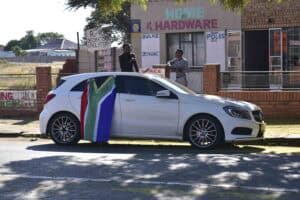 A car parked alongside the road with a South African flag hanging off it