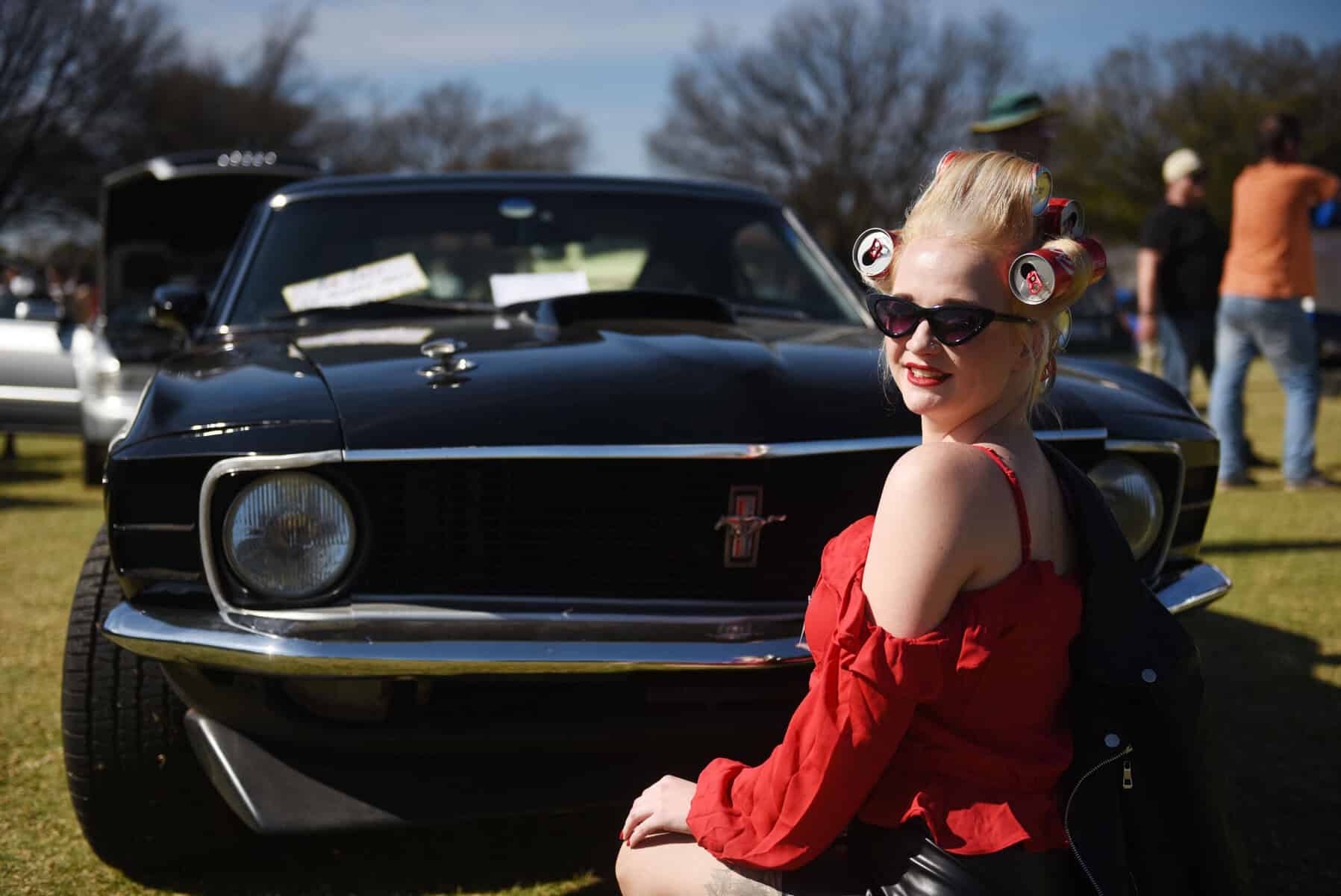 Chanelle Potgieter pose for a photograph next to a Ford Mustang Mach 1