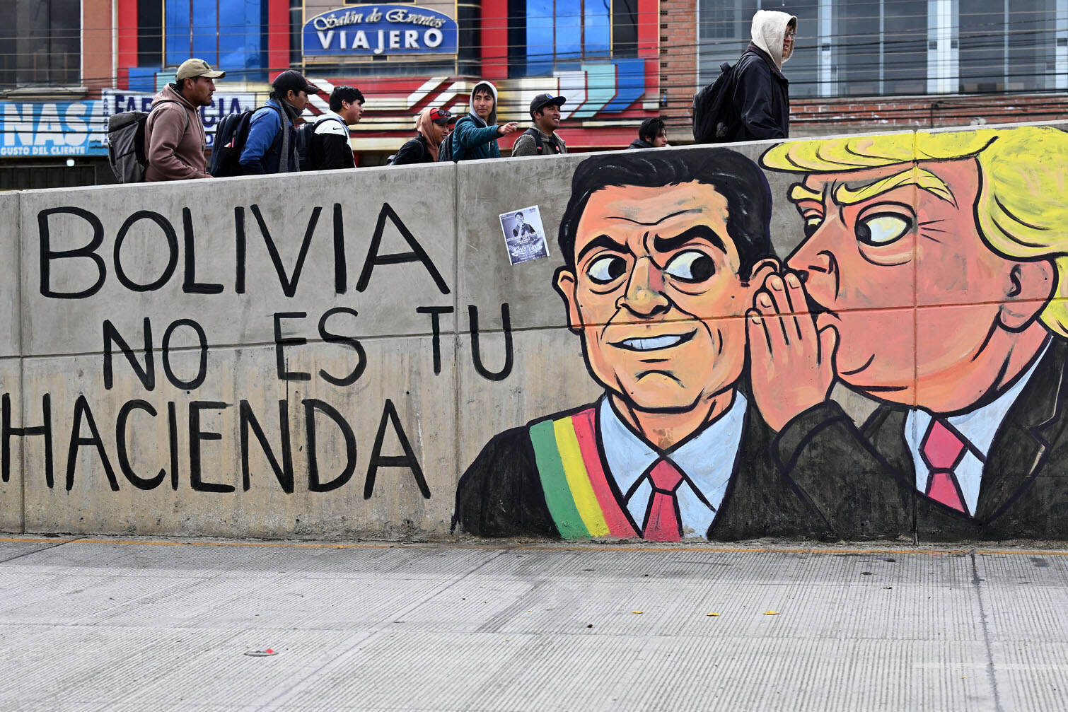 Youngsters walk past a wall displaying anti-government mural paintings