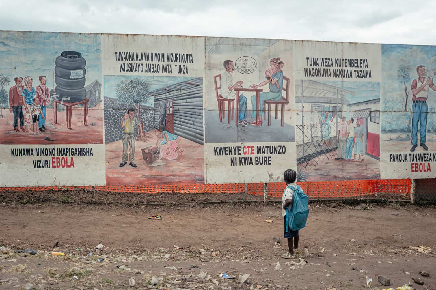 A child returning from school stops to look at Ebola awareness illustrations