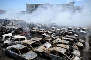 Fire personnel douse fire amidst charred abandoned vehicles
