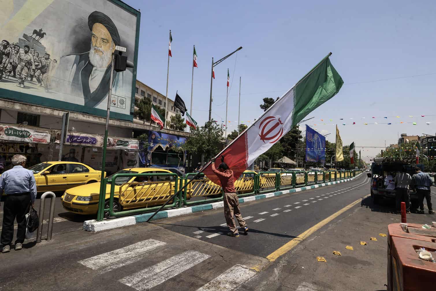 A worker raises a pole bearing the Iranian flag