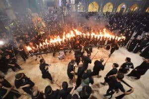 Shia Muslim mourners carry a large torch structure