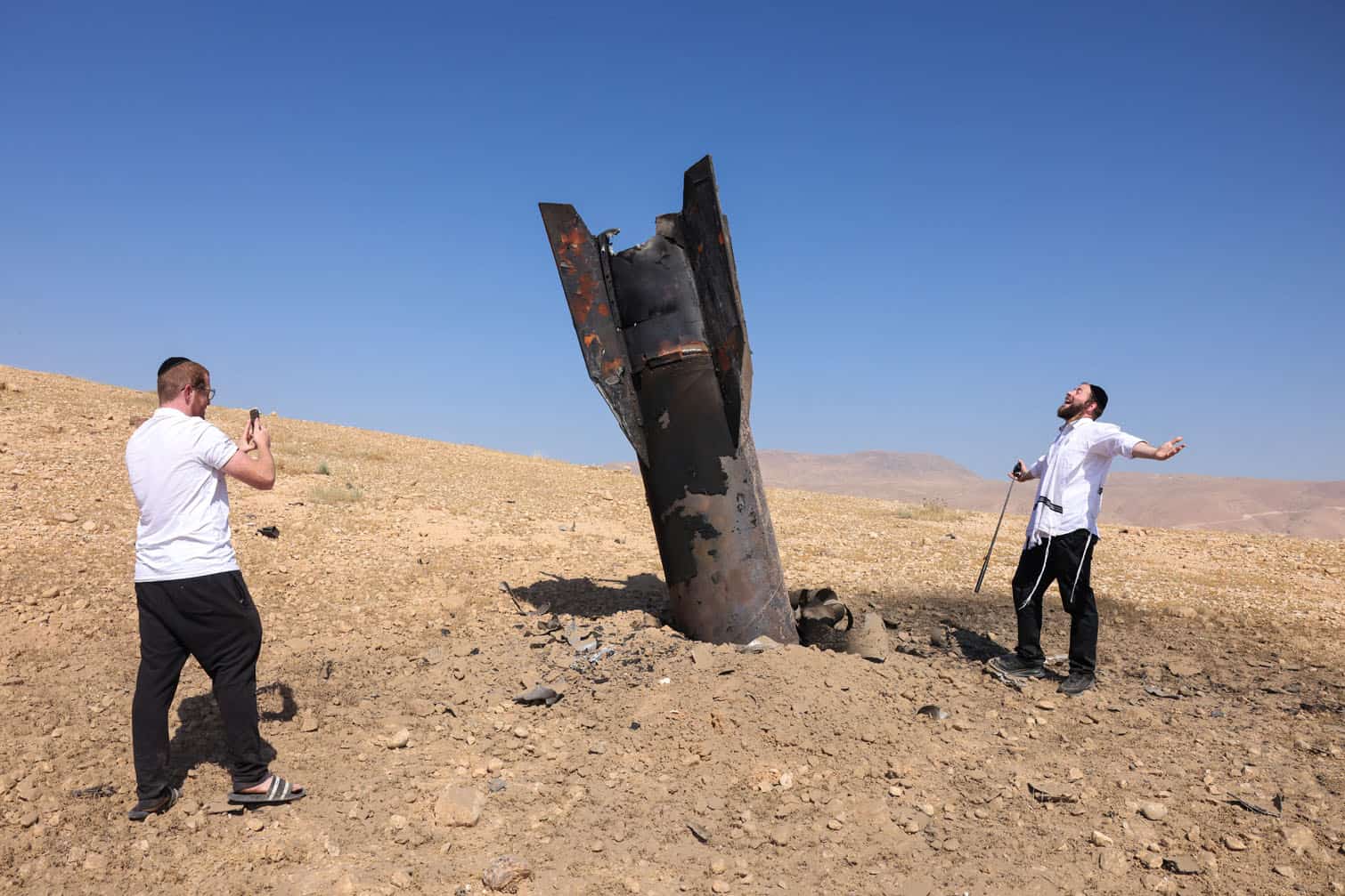 A man poses for a photo next to a fallen rocket
