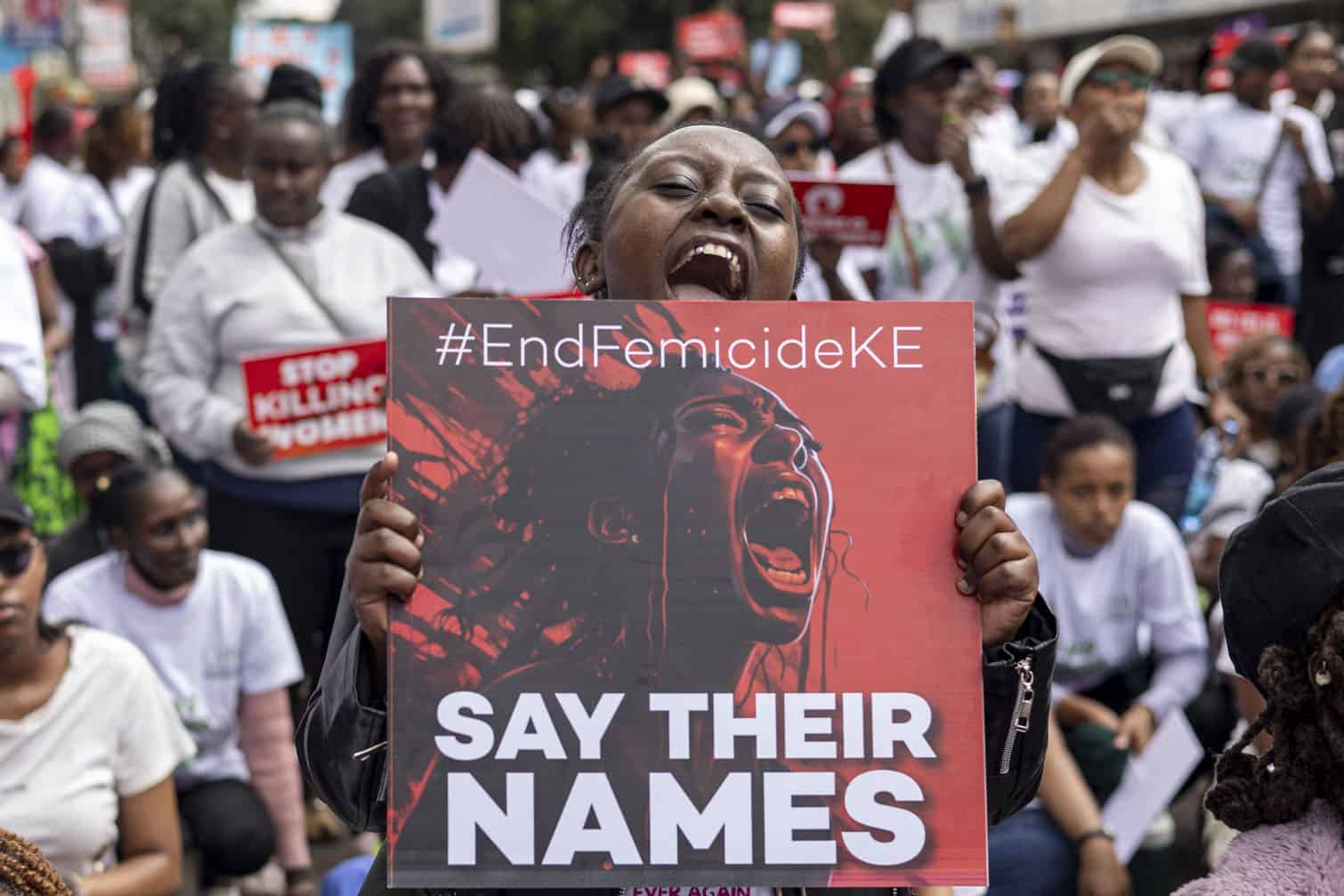 A protester holds a placard reading "Say their names"
