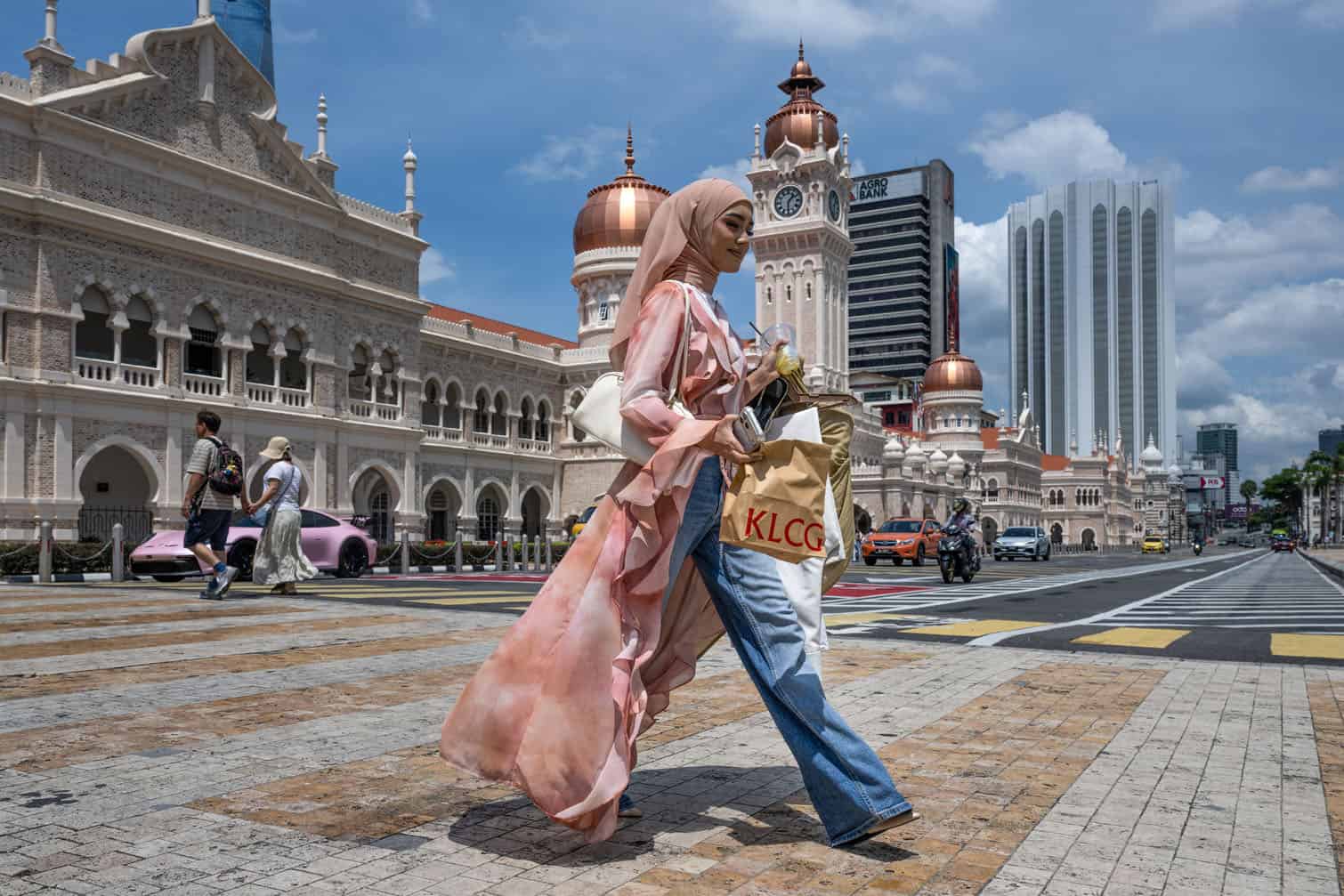 A woman crosses the street in front of the Sultan Abdul Samad building