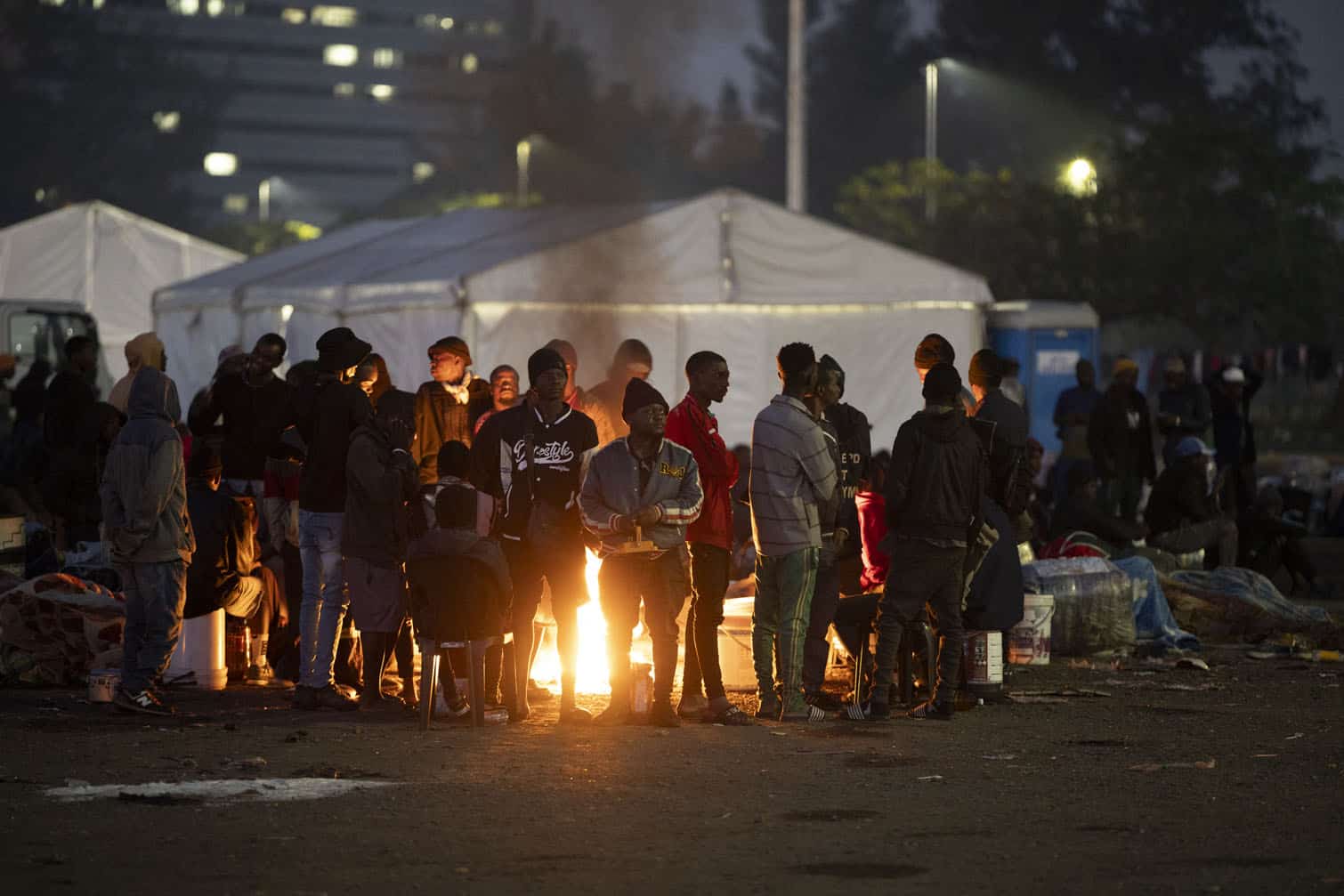 Undocumented migrants warm up by a camp fire