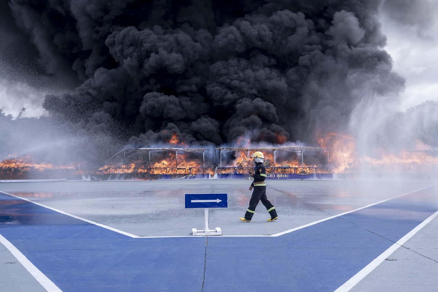 A firefighter walks past a burning pile of seized illegal drugs