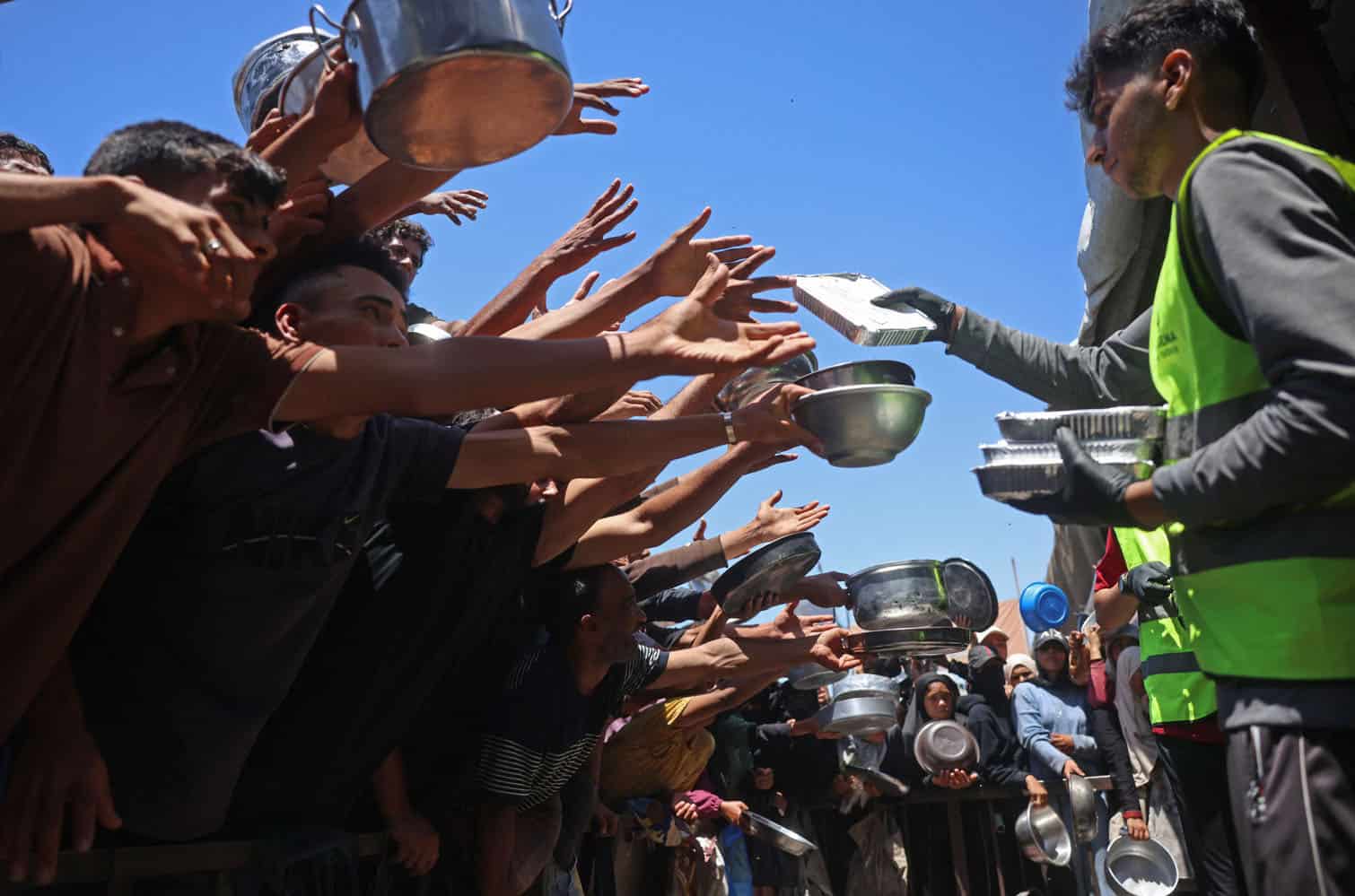 Displaced Palestinians gather to receive hot meals