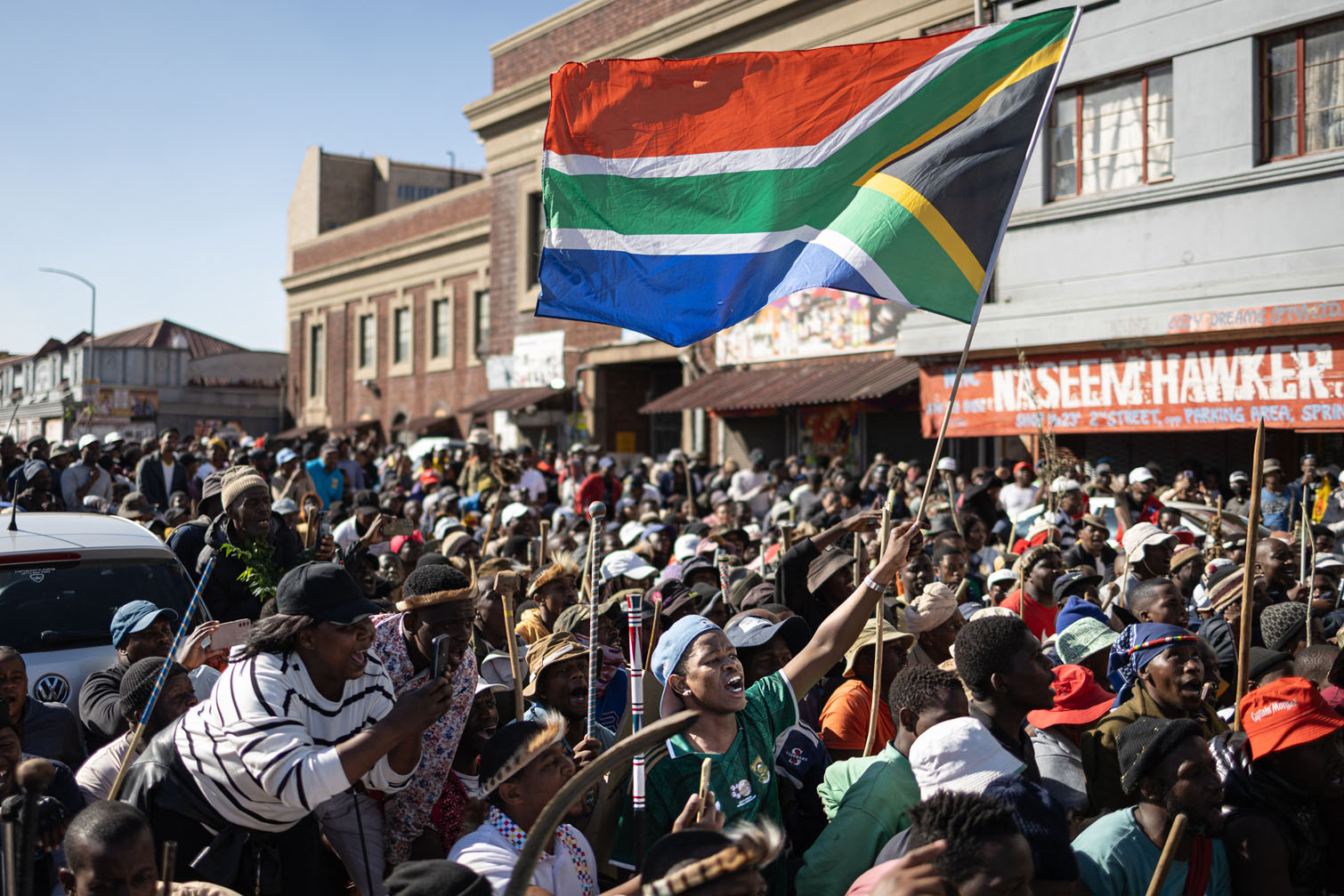 Protesters gather as one of them waves a South African flag