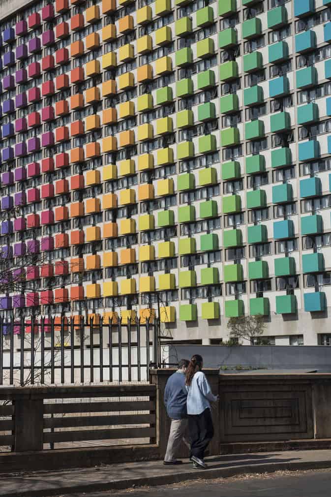 Pedestrians walk past the colourful Rise student accommodations