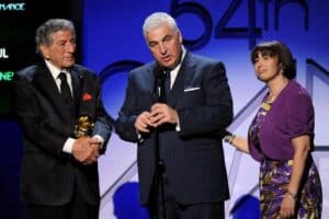 Tony Bennett (L) posing with the trophy he shares with late singer Amy Whinehouse listens to her father Mitch Winehouse as Janis Whinehouse looks on during the Pre-Telecast show at the Staples Center during the 54th Grammy Awards in Los Angeles, California, February 12, 2012. AFP PHOTO Joe KLAMAR Picture via ROBYN BECK / AFP