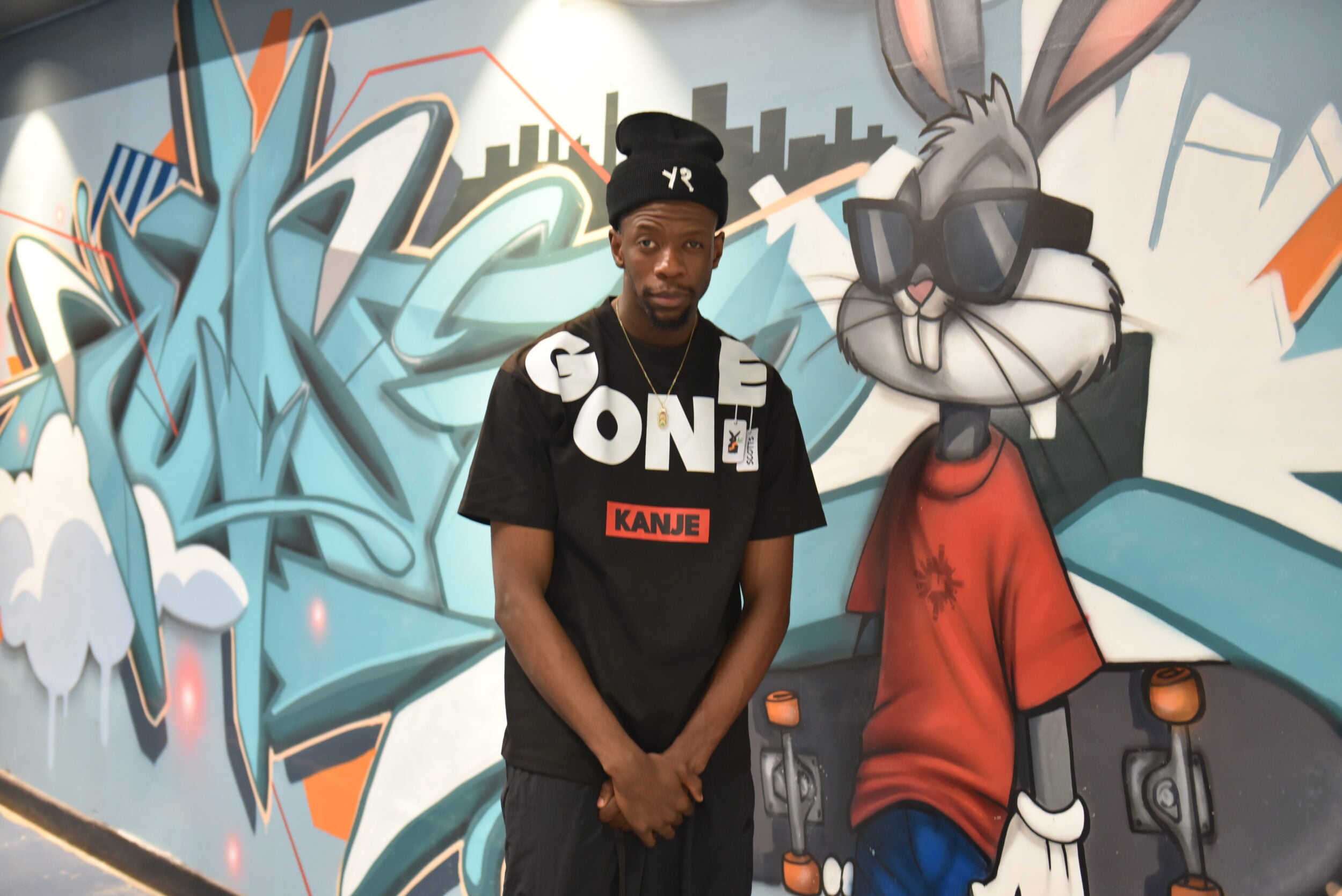 Robotboii poses at a wall of graffiti