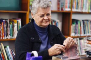 Maureen Freeman places Sellotape on books as she covers them at the Linden Library.