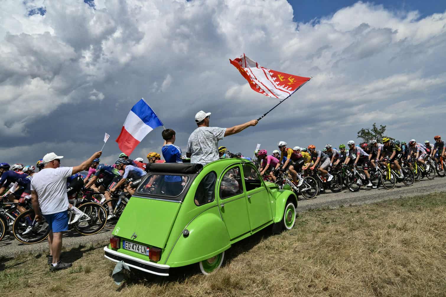 Spectators atop a Citroen 2CV wave flags