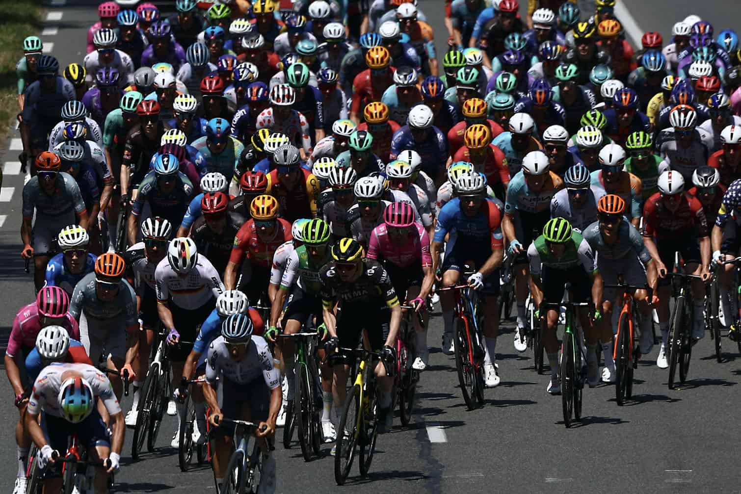 The pack of riders (peloton) cycles
