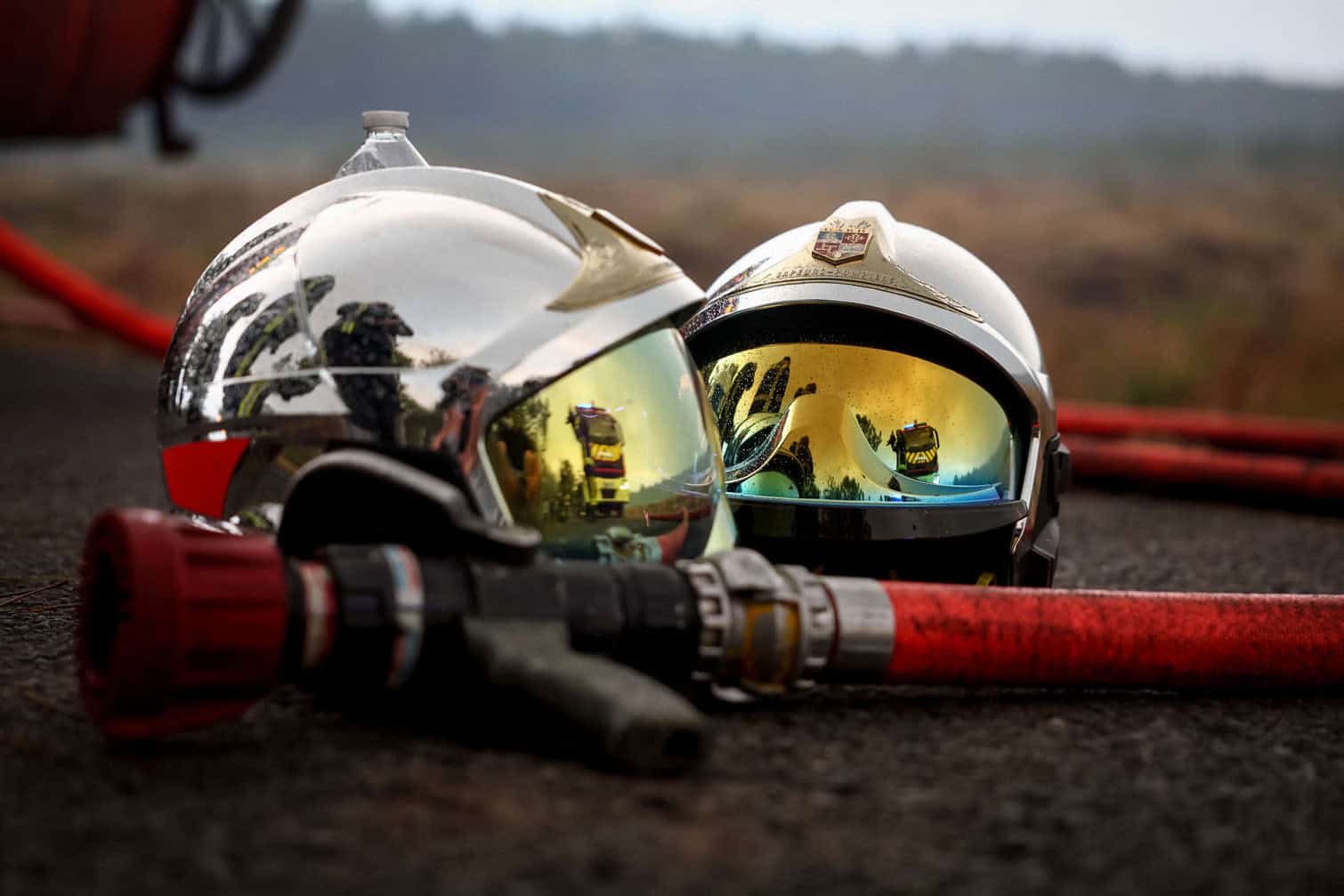 Two firefighter helmets and a fire hose are pictured on the ground as a forest fire rages in Saint-Jean-d'Illac, some 30km from Bordeaux, on July 26, 2026 as a wildfire has been ravaging the forest north of the Arcachon Basin (Gironde). The 220,000 people evacuated due to the massive wildfire in France's Gironde region will not be able to return home "until the fire has been brought under control", the local prefect said, also ruling out any normal workday on Monday in the affected towns, ahead of a possible worsening of the situation on Tuesday due to an expected rise in temperatures. (Photo by ROMAIN PERROCHEAU / AFP)