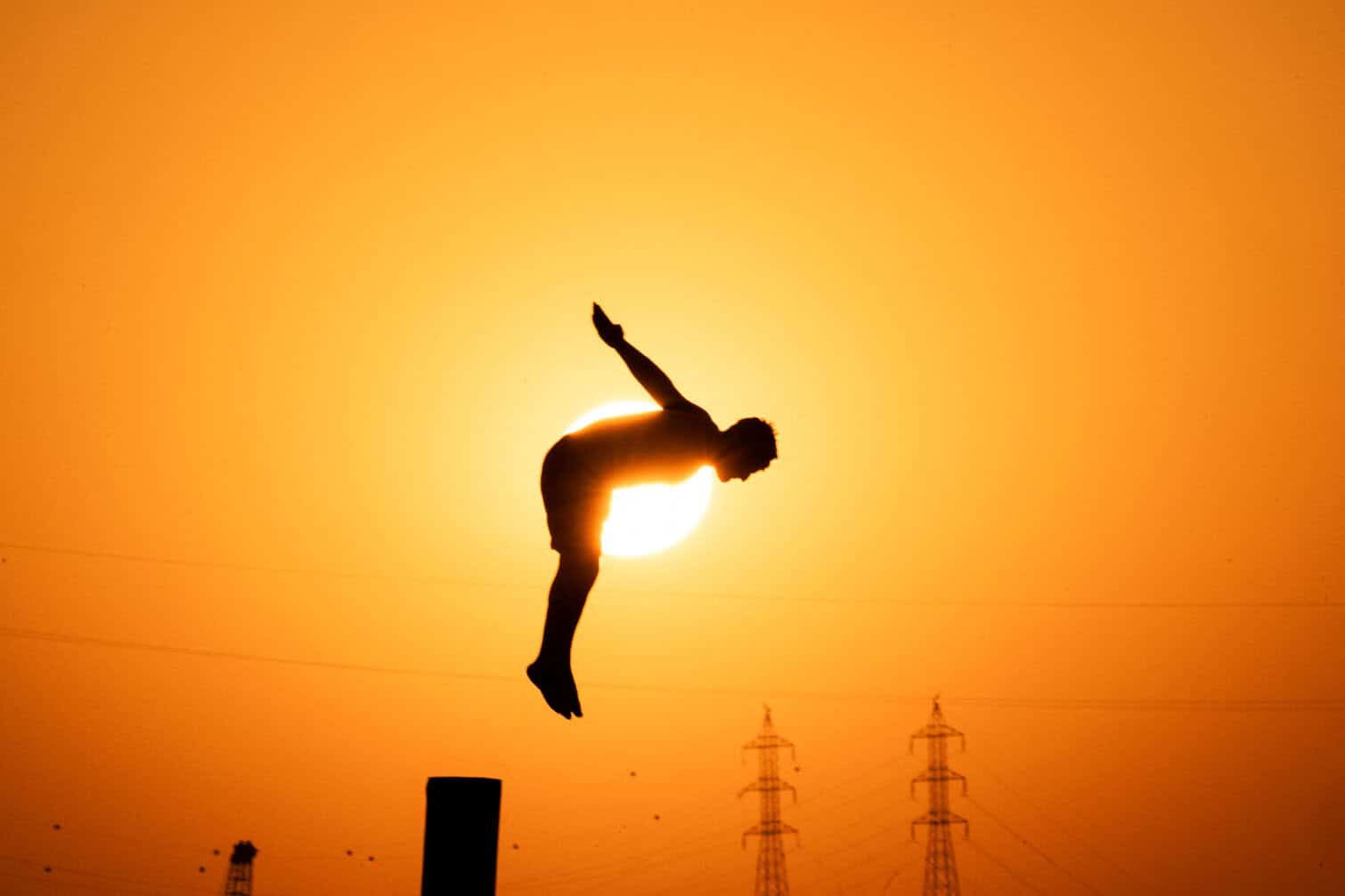 An Iraqi youth dives from a pole