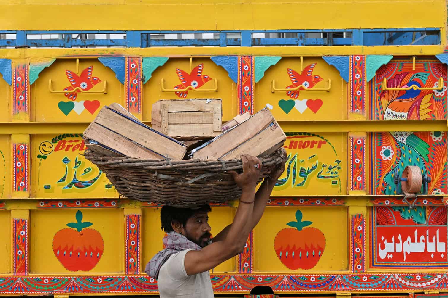 A labourer carries fruit baskets
