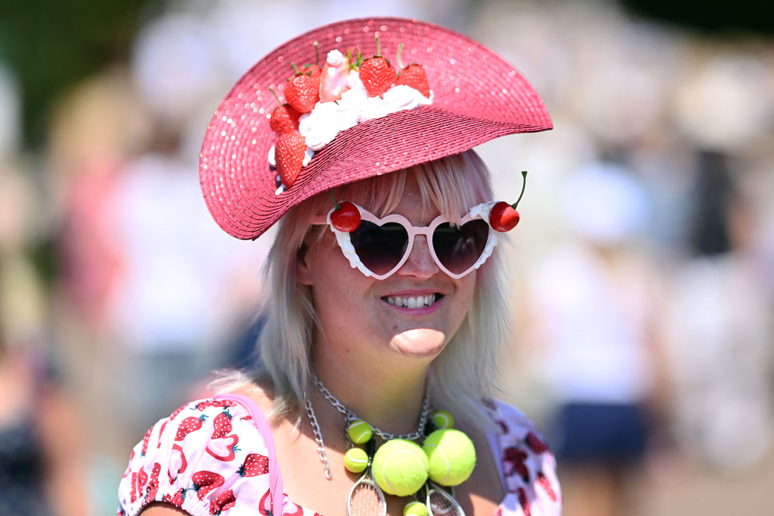 A spectator sporting a hat with strawberries and tennisballs