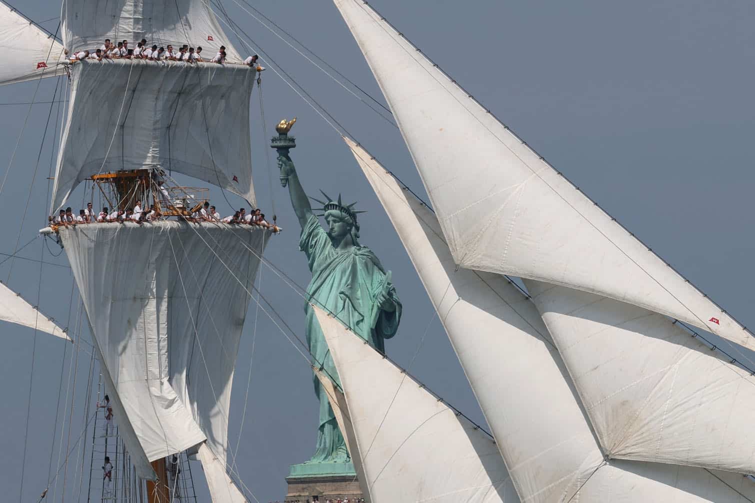 A tall ship sails past the Statue of Liberty