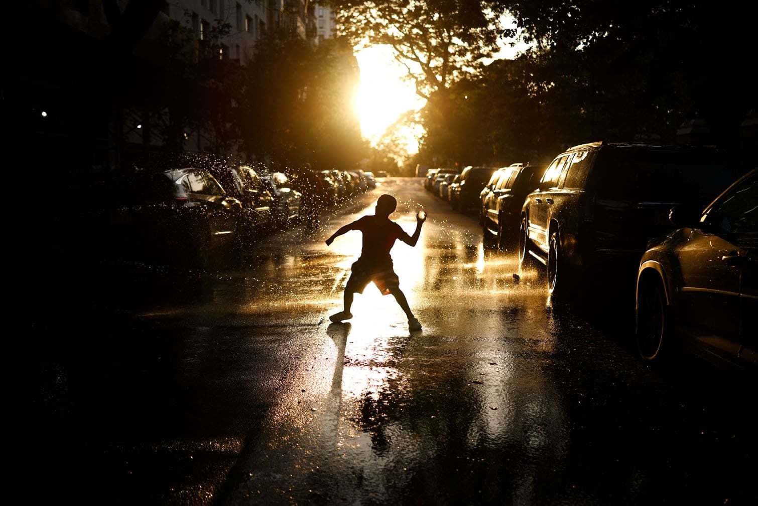 A kid plays on water-soaked pavement