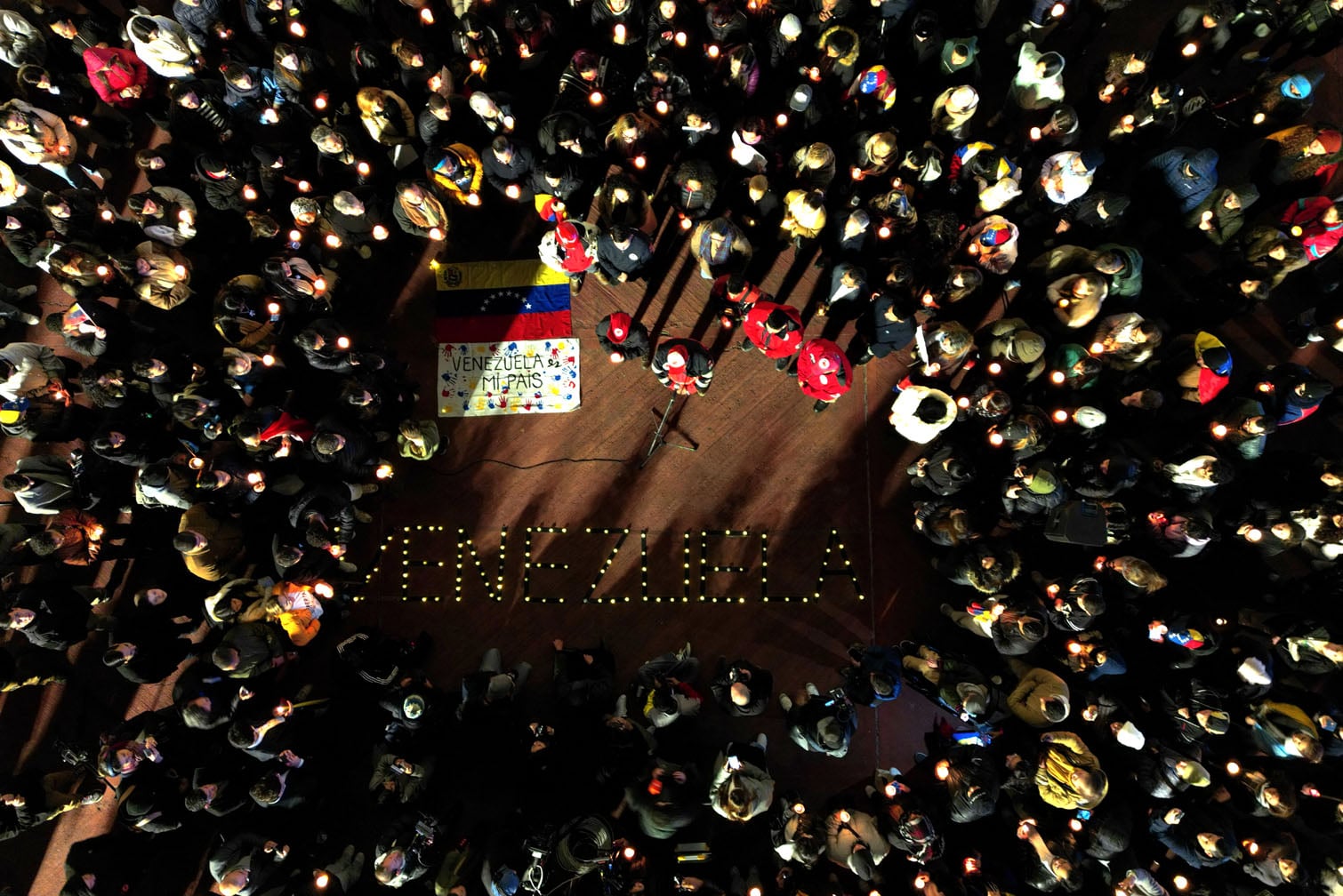 people holding lit candles and a Venezuelan flag