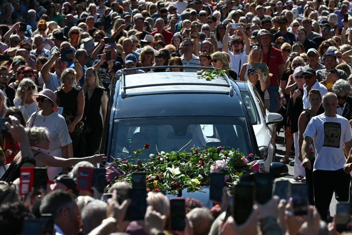 Mourners and fans line the streets to pay their respects as a hearse carrying the coffin of the late singer Bonnie Tyler is driven through her home town of Mumbles, southwest Wales, on August 15, 2026. Welsh singer Bonnie Tyler, best known for her powerful, haunting love song "Total Eclipse of the Heart" died in Portugal on July 8, 2026, aged 75. Picture JUSTIN TALLIS / AFP