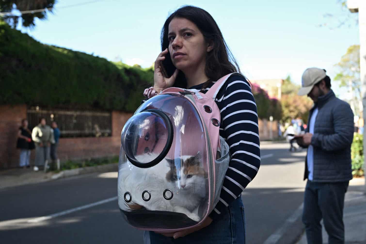 A woman carring her cat evacuates after an earthquake in Bogota on August 10, 2026. A strong earthquake struck Colombia on August 10 and was strongly felt in major cities such as Bogota and Cali, and even in Quito and Panama, according to the Colombian Geological Service and as confirmed by AFP reporters. (Photo by Raul ARBOLEDA / AFP)